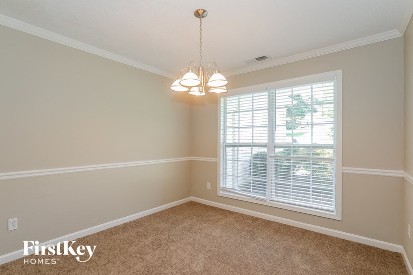 A room with a carpeted floor and a window with blinds.