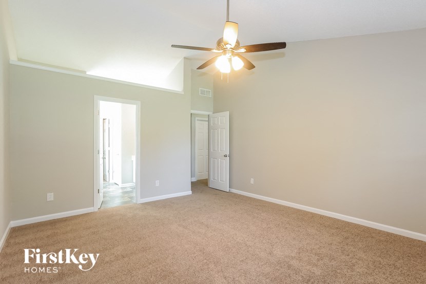A spacious room with a ceiling fan and two doors.