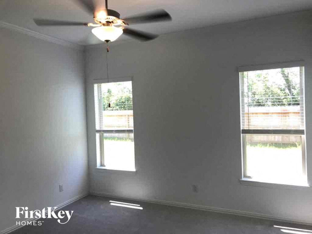 an empty room with a ceiling fan and two windows