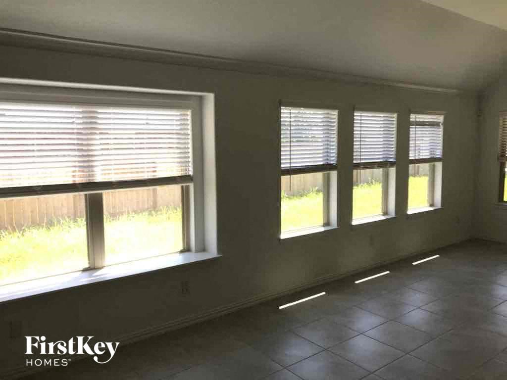 an empty living room with windows and a tiled floor