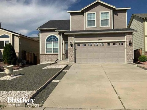 A two-story house with a garage and a driveway in front.
