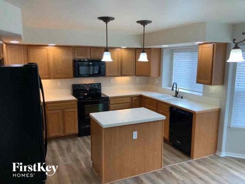 A kitchen with wooden cabinets and a black refrigerator.