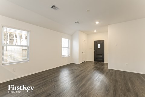 A spacious room with wooden flooring and a black door.