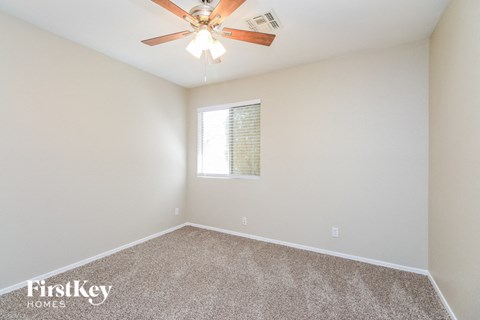 the spacious living room with ceiling fan and carpet