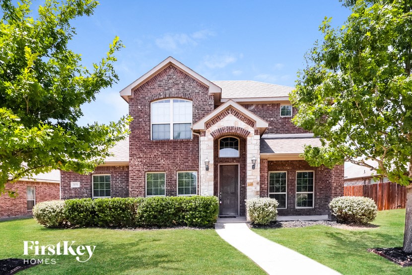 A brick house with a large front yard and a clear blue sky.