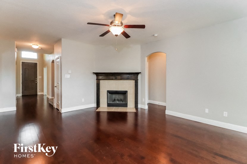 A spacious living room with a fireplace and a ceiling fan.