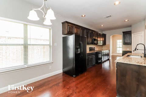 A kitchen with a black refrigerator and wooden cabinets.