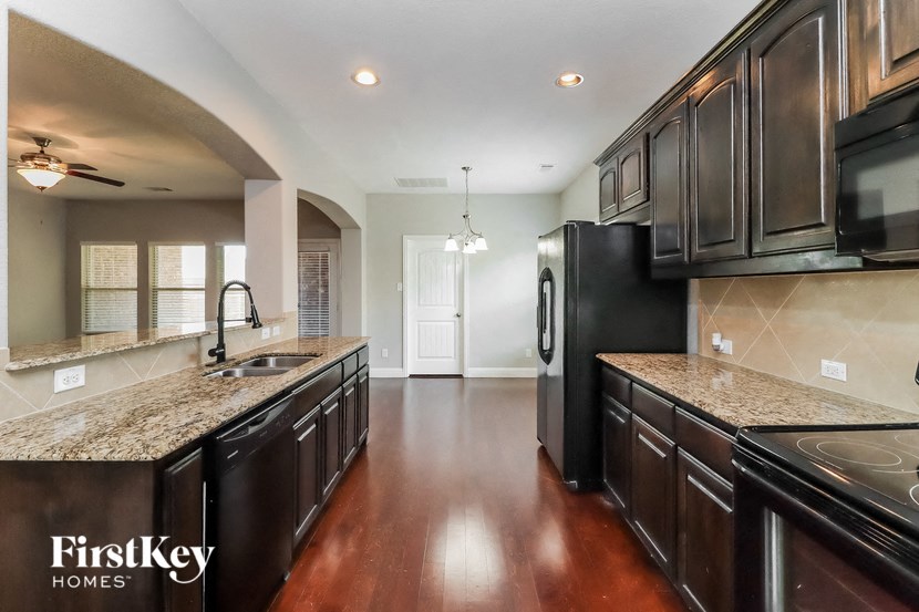 A kitchen with dark wood cabinets and a black refrigerator.