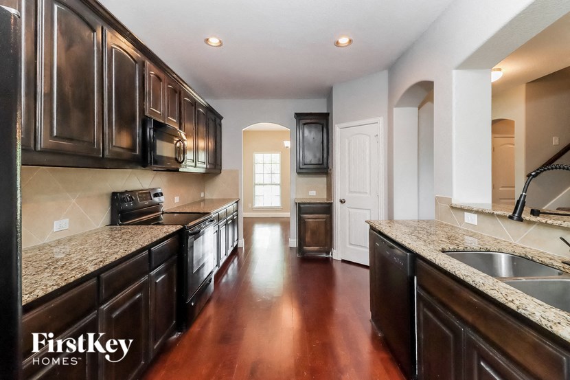 A kitchen with dark brown cabinets and a granite countertop.