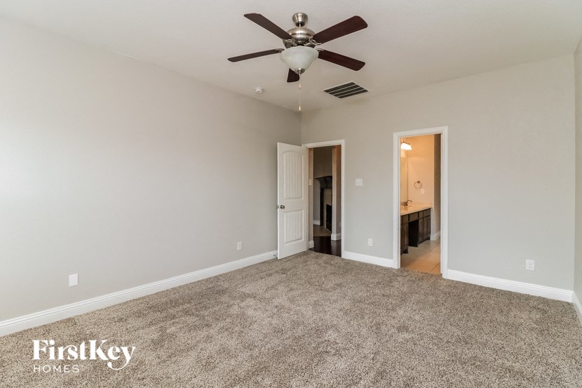 A spacious room with a carpeted floor and a ceiling fan.