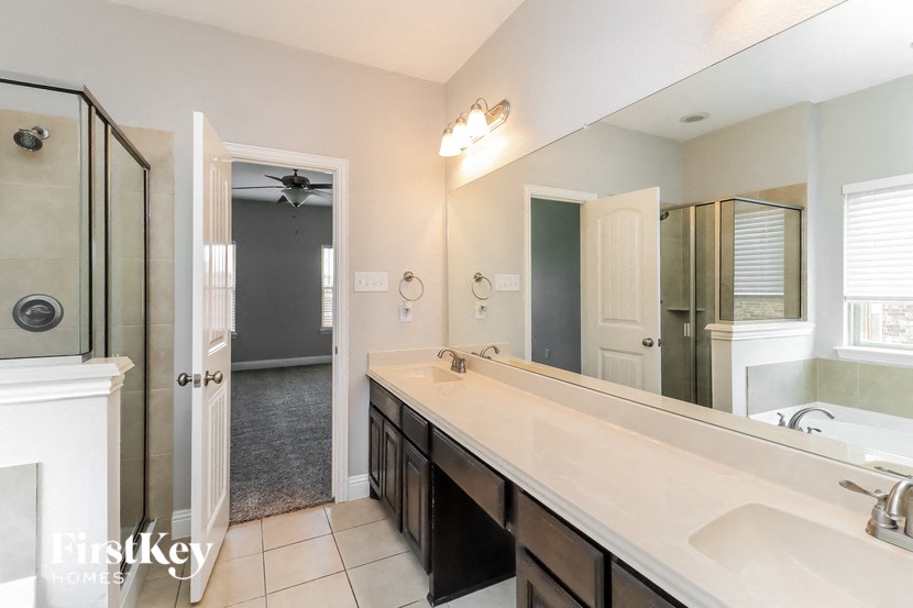 A bathroom with a large mirror, a sink, and a shower.