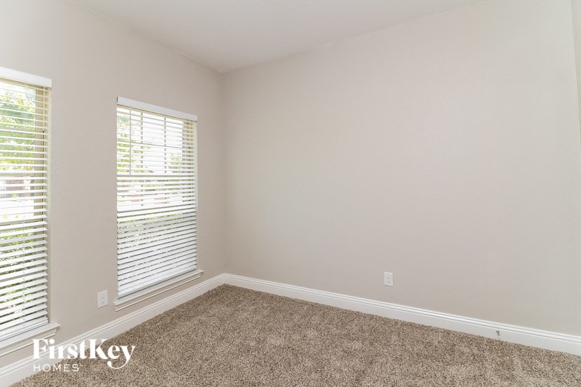 A room with a carpeted floor and a window with blinds.
