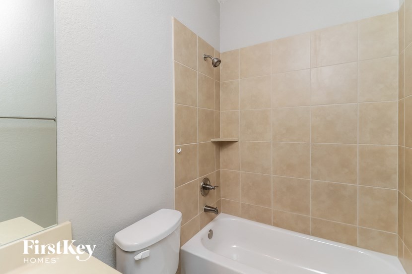A bathroom with a beige tile wall and a white toilet.