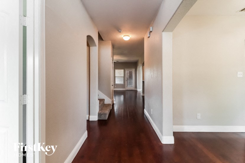 A long hallway with a wooden floor and white walls.