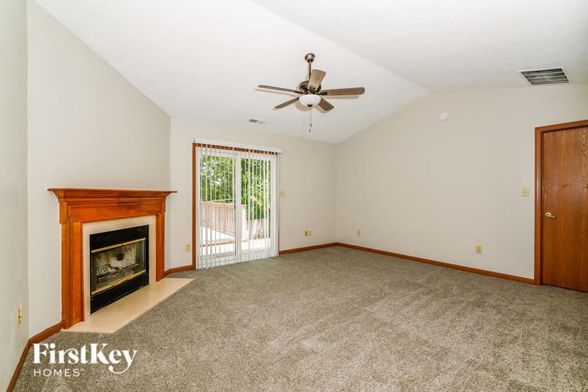 A spacious room with a fireplace and a ceiling fan.