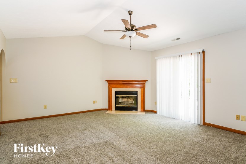 A spacious room with a fireplace and a ceiling fan.