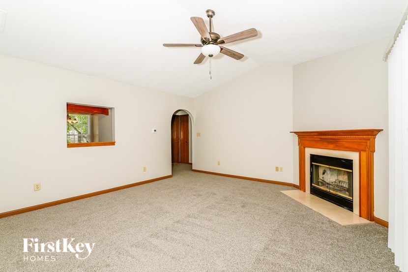 A spacious room with a fireplace and a ceiling fan.