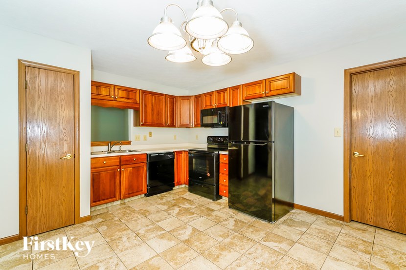 A kitchen with a tile floor and a refrigerator.