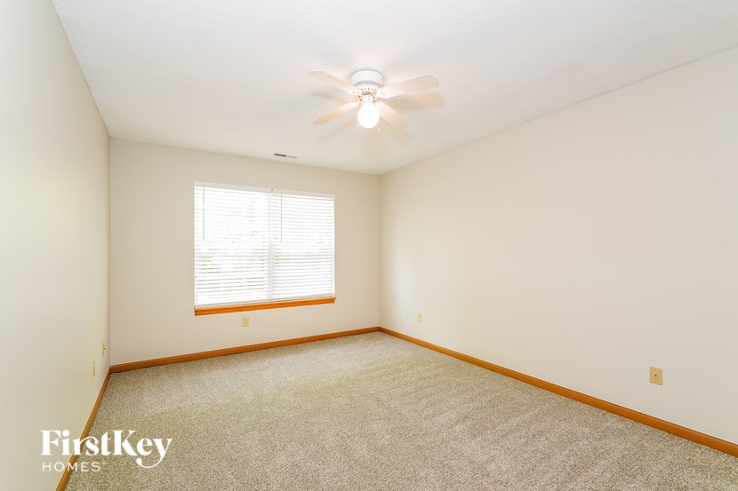 A room with a ceiling fan and a window with blinds.