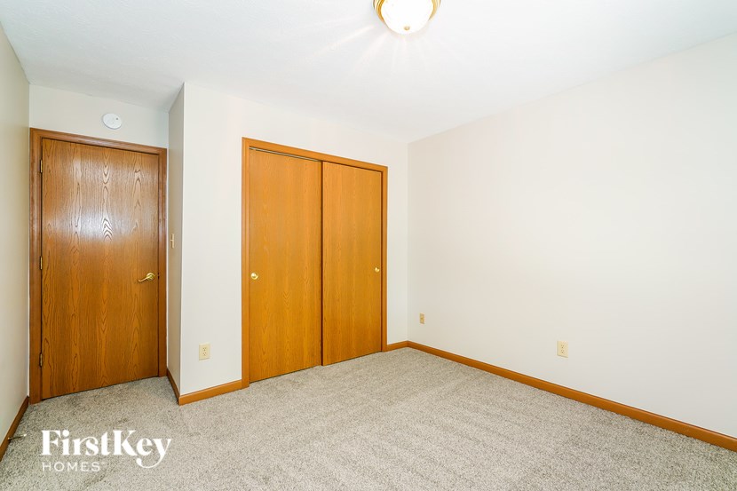 A bedroom with a carpeted floor and two wooden doors.