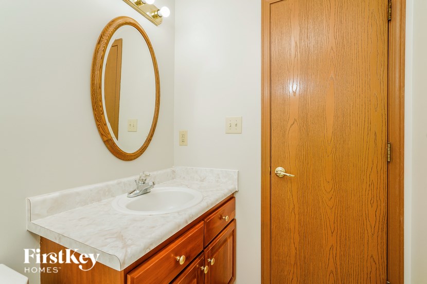 A bathroom with a sink, mirror and wooden door.