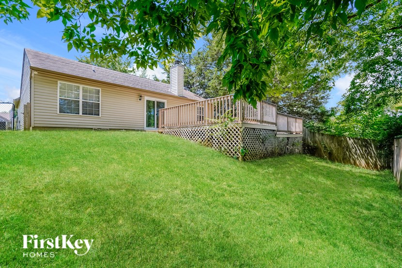 A house with a green lawn and a fence in front of it.
