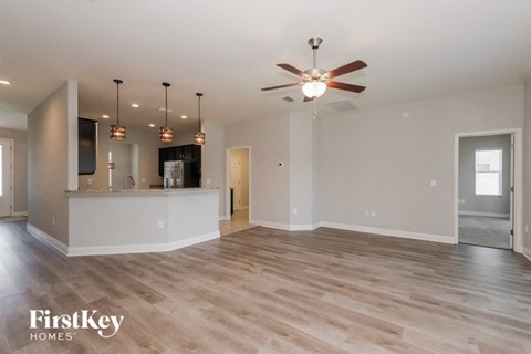 A spacious living room with a ceiling fan and lighting fixtures.