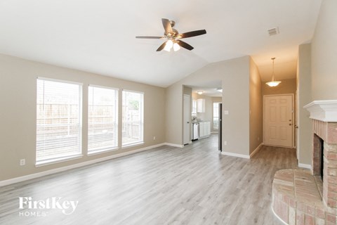A spacious living room with a fireplace and a ceiling fan.