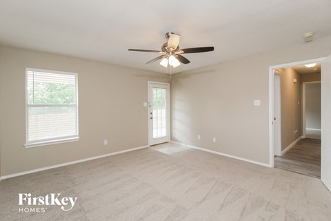 A spacious room with a ceiling fan and a door leading to another room.