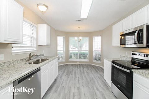 A kitchen with white cabinets and a granite countertop.