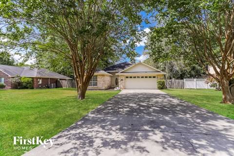 A house with a driveway and trees in front of it.