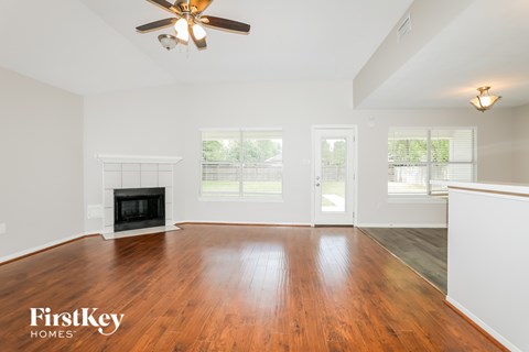 A spacious living room with a fireplace and a ceiling fan.