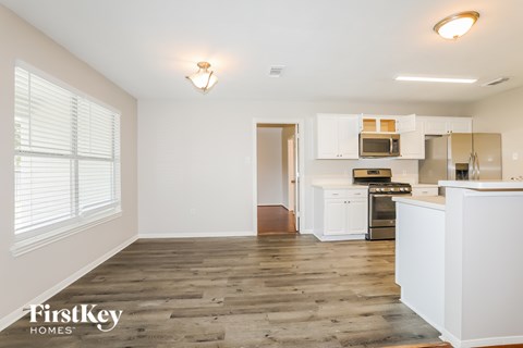 A kitchen with white cabinets and a wooden floor.