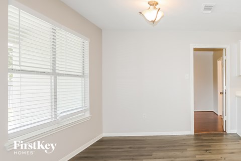 A room with wooden floors and a window with blinds.