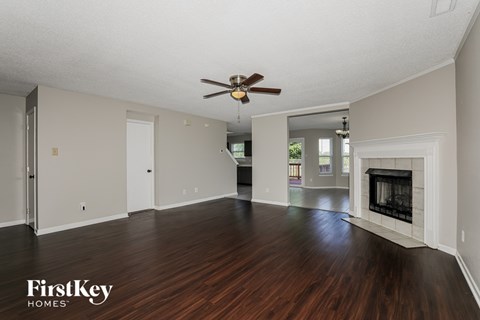 A spacious room with a fireplace and wood flooring.