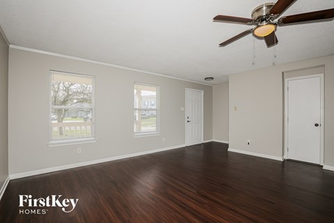A room with a ceiling fan and wooden floors.