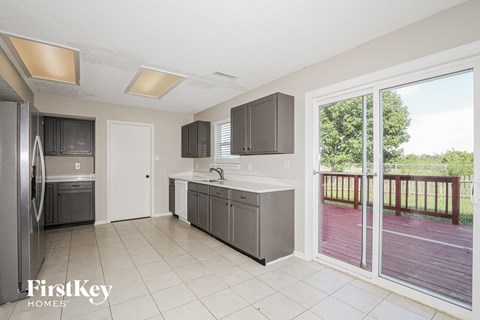 A kitchen with a refrigerator, sink, and cabinets.
