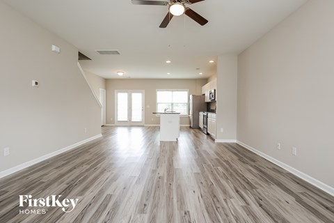 A spacious room with wooden floors and a ceiling fan.