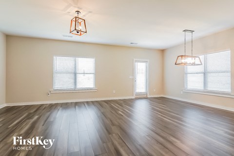 an empty living room with wood floors and two windows