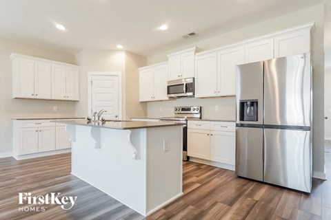 a kitchen with white cabinets and a stainless steel refrigerator
