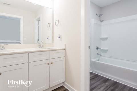 a white bathroom with a tub and a sink and a mirror