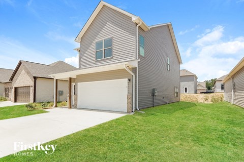 a gray house with a garage door and a green lawn