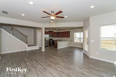 A spacious living room with a staircase and a ceiling fan.