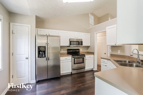 A kitchen with a refrigerator, oven, microwave, and sink.