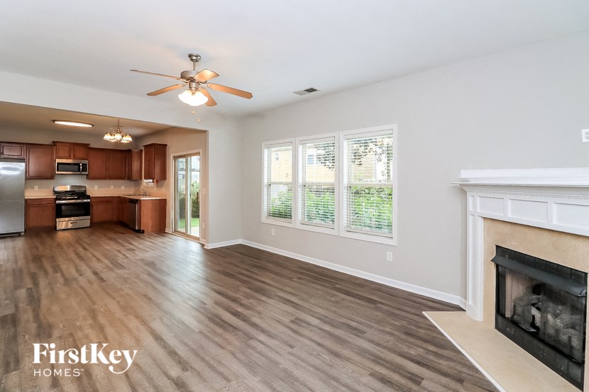 an empty living room with a fireplace and a kitchen