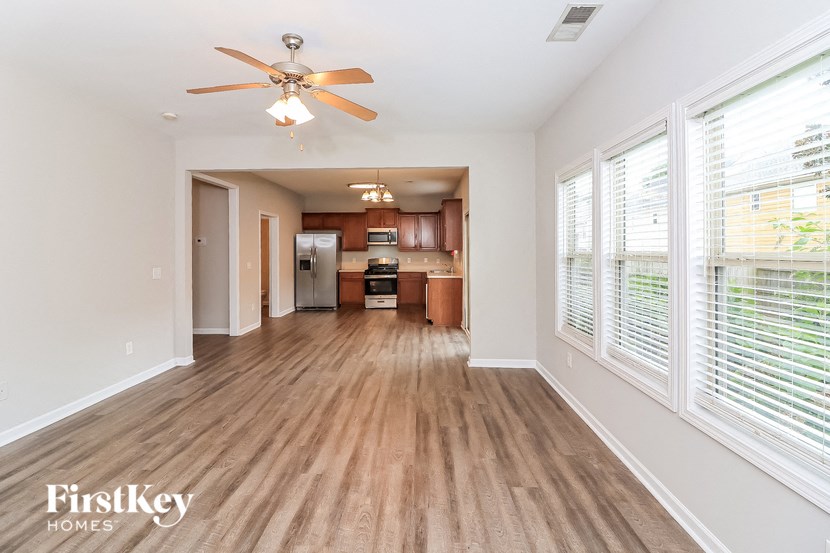an empty living room with a ceiling fan and a kitchen
