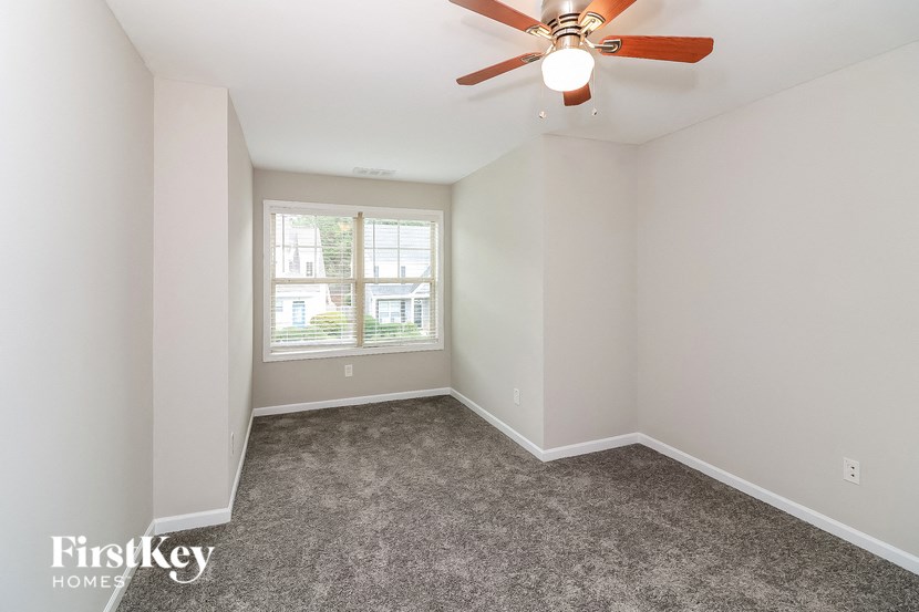 an empty room with a ceiling fan and a window