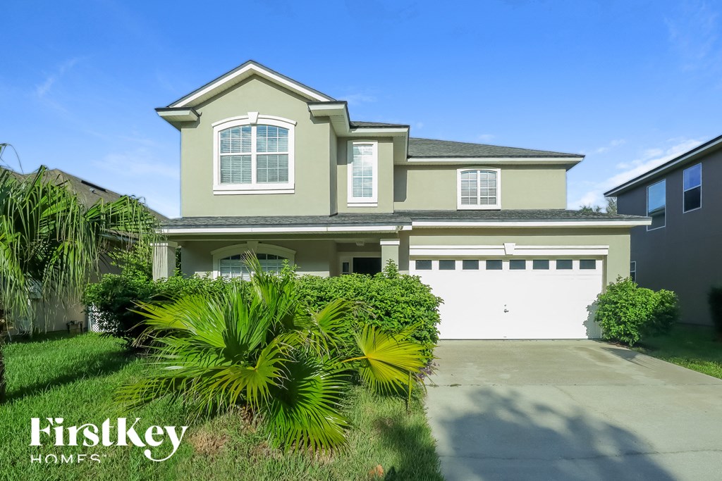 a house with a garage and palm trees in front of it