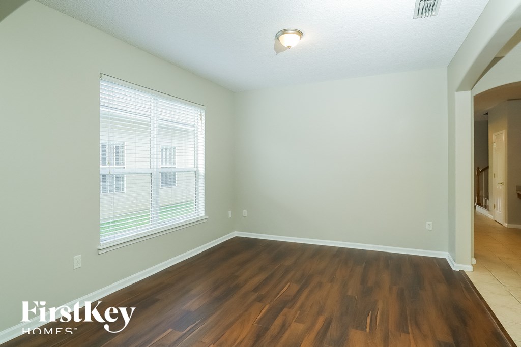 the spacious living room with hardwood flooring and a large window