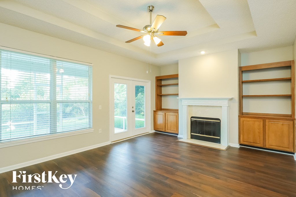an empty living room with a fireplace and a ceiling fan